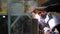 Welder worker welding the steel structure frame, poisonous fumes around him during welding, can cause cancer illness.