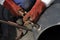 Welder worker welding a wide metal pipe tube with a oxy-fuel cutting torch