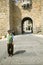 Well-dressed older man with hat walks through gate of walled city, Avila Spain, an old Castilian Spanish village