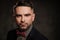 Well-groomed stylish young man with bow tie posing on dark background.