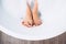 Well groomed woman`s legs in bath foam close up image