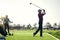 Well played. a focused young male golfer about to swing and play a shot with his golf club outside on a course.