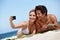 Well remember this summer forever. a happy young couple taking a selfie together at the beach.