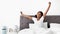 Well-rested black woman enjoying happy morning, stretching in bed