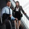 Well seasoned business travelers. a businessman traveling down an escalator in an airport with a businesswoman behind