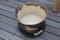 A well used worn out rusty top bowl spittoon placed on a wooden floor