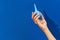 Wellgroomed womans hand holding enema on blue background