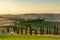 A wellknown Tuscan landscape with grain fields, cypresses and houses in the hills at sunset. Autumn rural landscape with