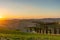 A wellknown Tuscan landscape with grain fields, cypresses and houses in the hills at sunset. Autumn rural landscape with