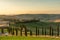 A wellknown Tuscan landscape with grain fields, cypresses and houses in the hills at sunset. Autumn rural landscape with