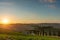 A wellknown Tuscan landscape with grain fields, cypresses and houses in the hills at sunset. Autumn rural landscape with