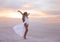 Wellness. Beautiful free confidence woman in white swimsuit enjoy summer vacation at sunset on the beach. Carefree blonde girl st