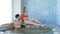 Wellness and Spa - young loving couple relaxing near water pool in hotel spa. Happy young woman and man relaxed resting