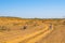 Wells in semi-desert. Girl walking on road in sand place