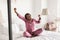 Wellslept African Female Yawning Stretching Arms Sitting In Modern Bedroom