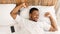Wellslept Black Guy Awakening In Bed Stretching Hands In Bedroom