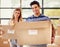 Were moving in together. Portrait of a smiling young couple carrying boxes on moving day.