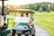 Were ready to step onto the green. a couple riding in a golf cart on a golf course.