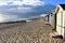 West Mersea beach with beach huts and dark threatening cloud.