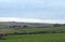 West yorkshire landscape with fields surrounded by stone walls with farmhouses and rolling moorland hills in the distance