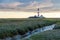 Westerhever lighthouse sand at sunset and clouds with canal in the foreground