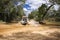 Western Australia â€“ Flooded Outback gravel road with 4WD car crossing the waterhole with splashing muddy water at the savanna