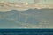 Western part of Tenerife seen from Gomera. Long lens shot. Blue sky with clouds, blue water under straight coast line. Canary