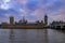 Westminster Palace and Big Ben covered in scaffolding for restoration viewed across the Thames at sunset in London, UK