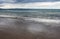 Wet beach as the tide recedes with blue mountains ranges in the distance under a stormy sky - Byron Bay NSW Australia