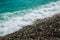 Wet black pebble beach covering with frothy water of waves. Background, texture