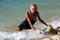 Wet blond kneeling in surf