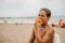 Wet boy sitting and eating peach on the beach