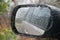 Wet car window with side mirror in rain weather