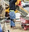 Wet cement off loaded by construction workers using a shovel from a cement truck chute into a wheelbarrow