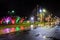 Wet city street at night, with colorful decorative lighting in the trees