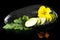 Wet courgettes cut into slices with flower and leaf on black