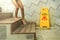 Wet floor sign board beside wooden stairs at swimming pool