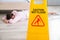 Wet Floor Sign With Fainted Housekeeper Lying On Floor