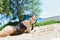 A wet girl with dark hair in a black bathing suit rest on the sand after swimming in the river