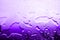 Wet glass surface in drops of water, violet gradient, texture of spilled water in bright purple colors, abstract background
