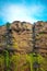 Wet Hard Rock Vertical Cliff with Water Seepage and Blue Sky.