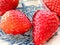 Wet juicy luscious strawberries shiny on blue white dutch plate close up