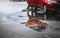 Wet parking spaces after hard rain fall with reflection in puddle on the ground.