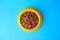 Wet pet food in feeding bowl on light blue background, top view