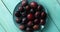 Wet plums on blue plate on table