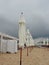 Wet sunbeds and umbrellas on the sea beach during heavy rain storm. Rolled up parasol on the beach against dark cloudy