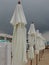 Wet sunbeds and umbrellas on the sea beach during heavy rain storm. Rolled up parasol on the beach against dark cloudy