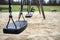 Wet swings after rain on a deserted playground, spring day, on a dim background of lawn and forest