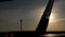 Wet tail of the aircraft on runway and radar tower in the distance at sunset.