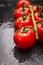 Wet tomatoes branch on black slate background